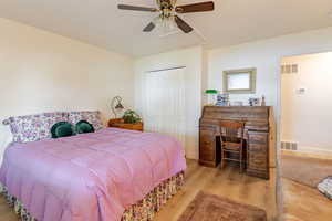 Bedroom featuring wood finished floors, a closet, ceiling fan, and attic access
