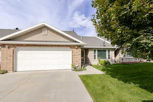 Ranch-style home featuring a front yard, concrete driveway, a shingled roof, an attached garage, and brick siding