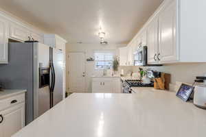 Kitchen with white cabinetry and appliances with stainless steel finishes