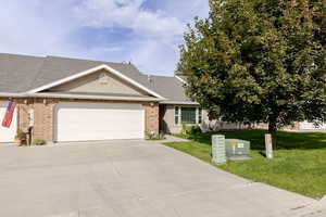 Single story home featuring a shingled roof, concrete driveway, a front lawn, and brick siding
