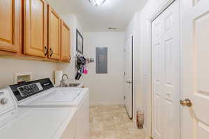 Laundry room featuring cabinet space, electric panel, separate washer and dryer, and a textured ceiling