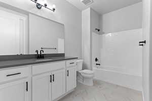 Bathroom with shower / washtub combination, vanity, light marble finish floors, and a textured ceiling