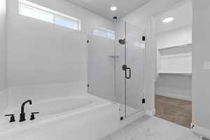 Bathroom with a bath, a shower stall, light marble finish flooring, a spacious closet, and recessed lighting