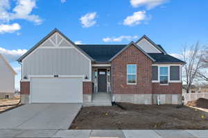 View of front of property featuring board and batten siding, brick siding, concrete driveway, a shingled roof, and an attached garage