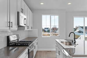 Kitchen with stainless steel appliances, white cabinets, light wood finished floors, recessed lighting, and decorative backsplash