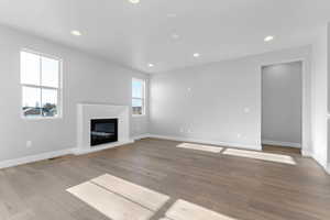 Unfurnished living room featuring a glass covered fireplace, light wood-style flooring, and recessed lighting
