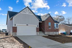 View of front of house featuring brick siding, concrete driveway, board and batten siding, and a garage