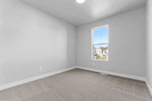 Empty room featuring light colored carpet and a textured ceiling