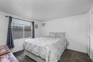 Bedroom with dark carpet and a wall mounted air conditioner