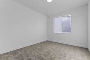 Empty room featuring light carpet and baseboards