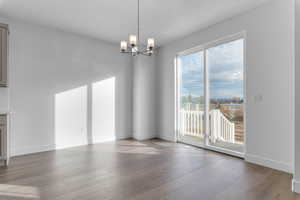 Unfurnished dining area with hardwood / wood-style flooring and a chandelier