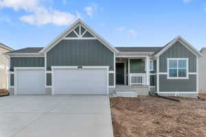 View of front facade with board and batten siding, an attached garage, a porch, driveway, and a shingled roof