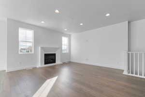 Unfurnished living room with a glass covered fireplace, hardwood / wood-style floors, recessed lighting, and a textured ceiling