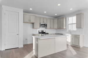 Kitchen featuring backsplash, recessed lighting, stainless steel appliances, a kitchen island, and light wood-style floors