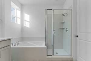 Bathroom featuring vanity, a garden tub, a shower stall, and light tile patterned flooring