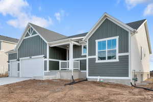 Modern farmhouse with board and batten siding, a porch, driveway, a shingled roof, and a garage