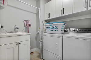 Laundry room with cabinet space, washer and dryer, and light tile patterned floors