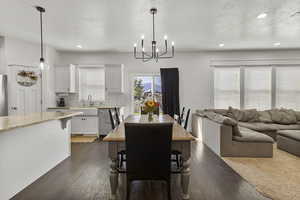 Dining area with a textured ceiling, dark wood-style flooring, recessed lighting, and a chandelier