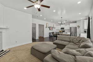 Living room featuring recessed lighting, a ceiling fan, a chandelier, and dark carpet