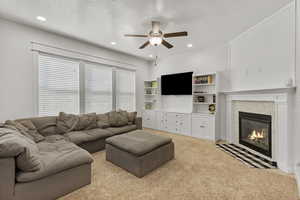 Living area featuring light carpet, a fireplace, ceiling fan, recessed lighting, and a textured ceiling