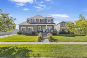View of front of property with a porch, a front lawn, stucco siding, and stone siding