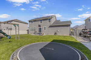 Rear view of house with a patio area, a playground, roof mounted solar panels, and stucco siding