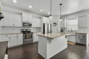 Kitchen with tasteful backsplash, stainless steel appliances, white cabinets, light stone countertops, and recessed lighting