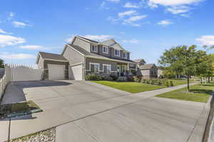 View of front of property featuring stucco siding, driveway, an attached garage, a porch, and stone siding