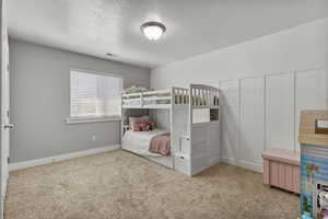 Bedroom with a textured ceiling and light colored carpet