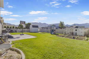 Fenced backyard featuring a mountain view, a shed, and a garden