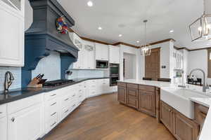 Kitchen with glass insert cabinets, dark wood-style flooring, hanging light fixtures, decorative backsplash, and dark stone counters