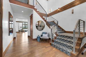 Stairway featuring wood finished floors, recessed lighting, and a high ceiling