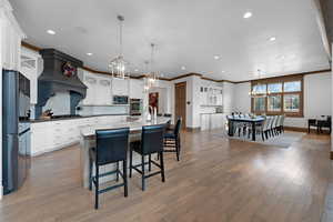 Kitchen featuring a chandelier, a center island with sink, hanging light fixtures, a breakfast bar area, and crown molding
