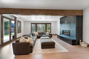 Living area featuring light wood finished floors, beam ceiling, and a tiled fireplace