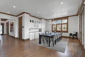 Dining space with crown molding, dark wood-style floors, recessed lighting, and a chandelier