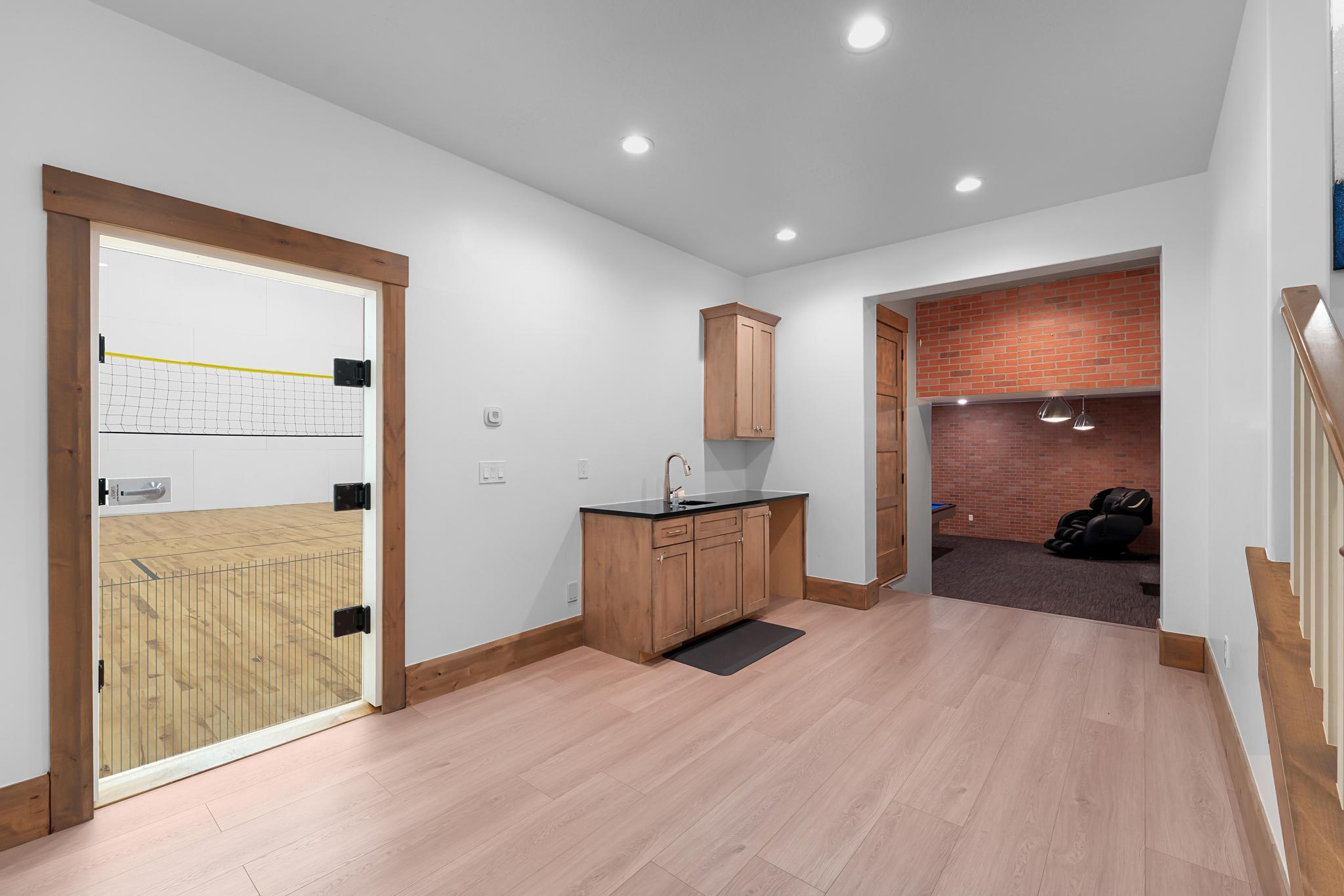 Bar featuring light wood-type flooring, brick wall, recessed lighting, and dark stone countertops
