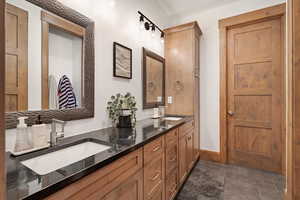 Bathroom with double vanity and dark tile patterned flooring