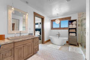 Full bath with vanity, a shower stall, a freestanding bath, a textured ceiling, and ensuite bathroom