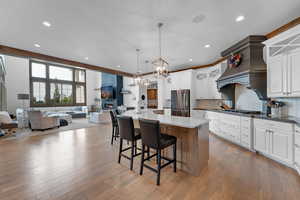 Kitchen with pendant lighting, open floor plan, a kitchen bar, tasteful backsplash, and white cabinetry