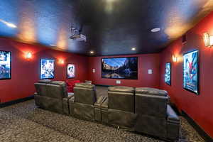 Carpeted home theater room featuring a textured ceiling and recessed lighting