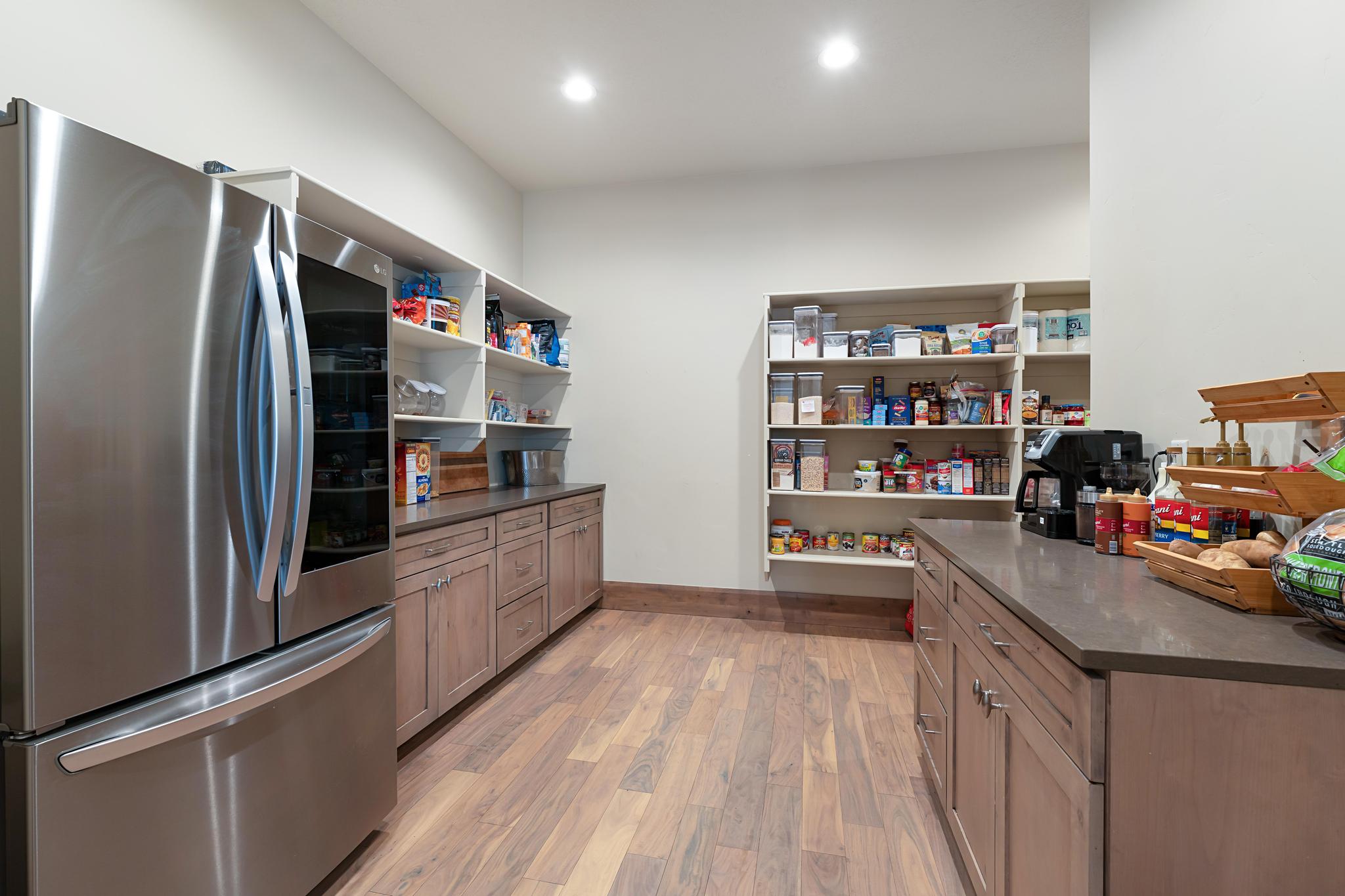 Kitchen with smart refrigerator, light wood-style floors, open shelves, brown cabinets, and dark stone counters