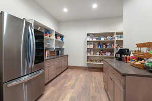 Kitchen with smart refrigerator, light wood-style floors, open shelves, brown cabinets, and dark stone counters