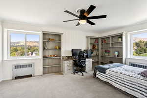 Carpeted bedroom featuring radiator, ornamental molding, ceiling fan, and an office area