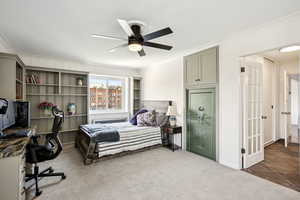 Bedroom featuring dark carpet, crown molding, a ceiling fan, radiator, and an office area