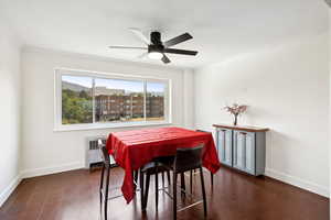 Dining area featuring crown molding, radiator, dark wood-type flooring, and a ceiling fan