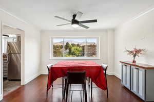 Dining area featuring dark wood-type flooring, ornamental molding, a mountain view, and a ceiling fan