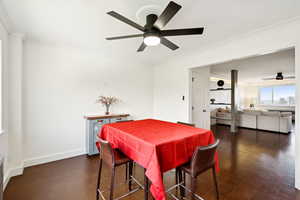 Dining space with ceiling fan, crown molding, and dark wood finished floors