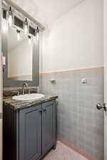Bathroom with vanity, tile walls, light tile patterned floors, and wainscoting