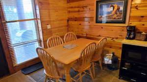 Dining area featuring wooden walls and dark colored carpet