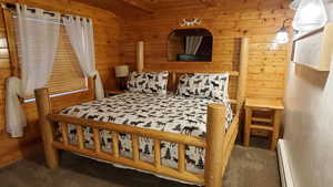 Carpeted bedroom with wooden walls and baseboard heating